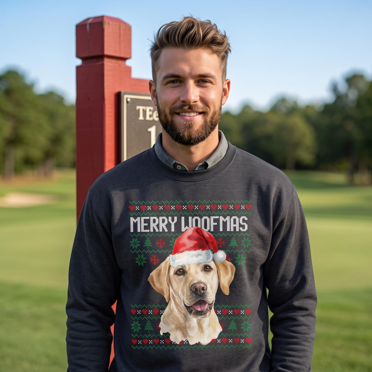 May include: A dark gray long-sleeve sweatshirt featuring a graphic of a yellow Labrador retriever wearing a red and white Santa hat. The text MERRY WOOFMAS is printed above the dog, surrounded by a green and red holiday-themed knit pattern.