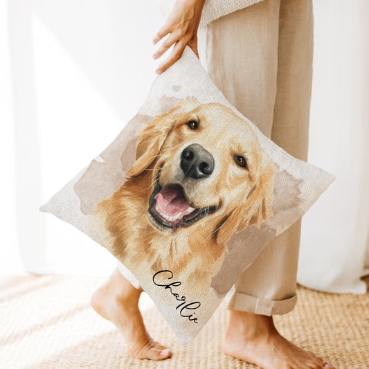 Personalized pet pillow featuring a watercolor-style portrait of a smiling Golden Retriever named Charlie, printed on a beige woven fabric pillow cover, held by a person in neutral-toned clothing.