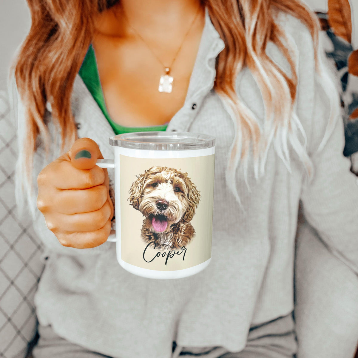 Person holding a white insulated tumbler featuring a custom illustration of a fluffy dog named Cooper, with light brown curls and a happy expression. The background is cozy and neutral, highlighting the personalized mug.