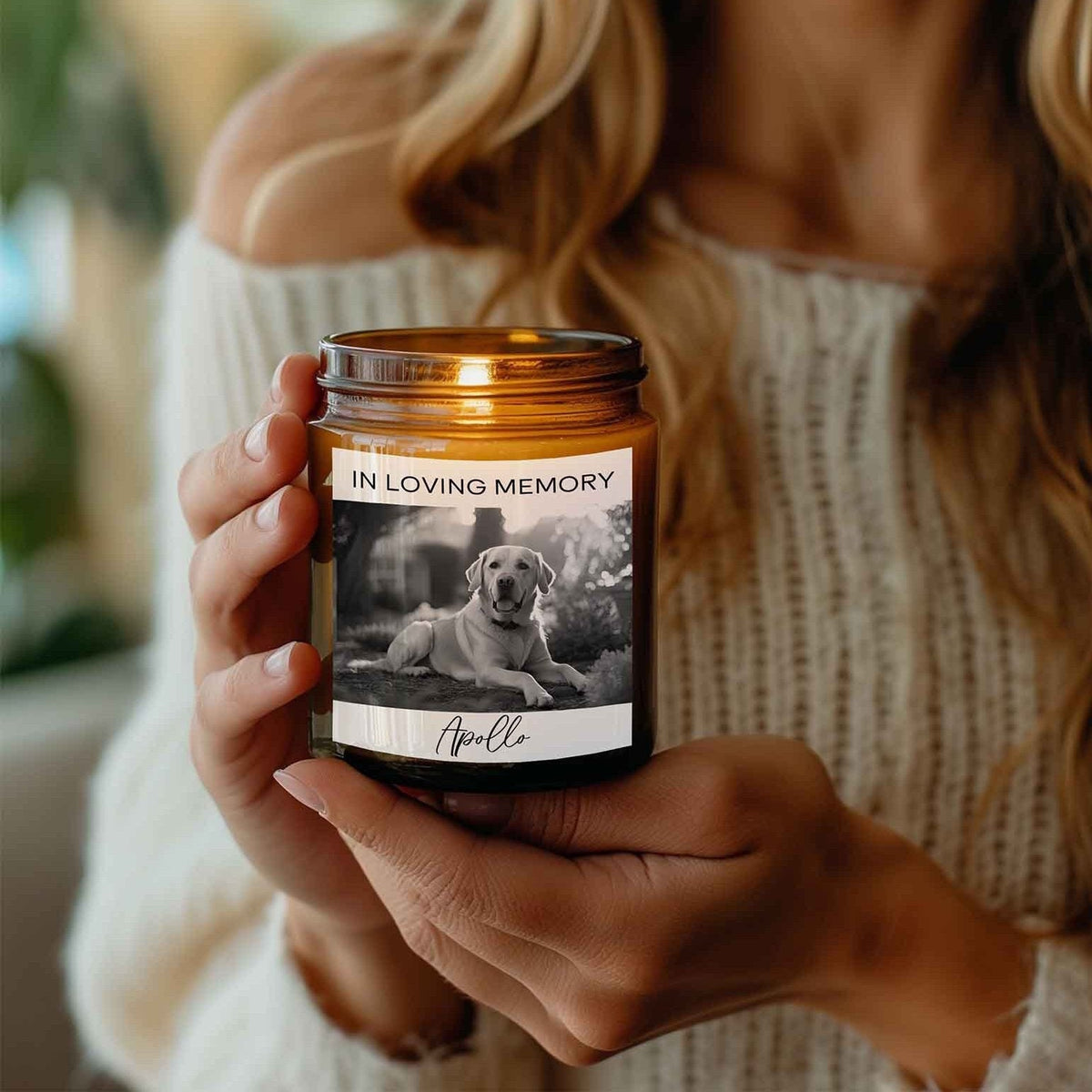 Amber jar candle customized with a black-and-white photo of a dog and the text 'In Loving Memory,' held by a woman in a cozy setting.