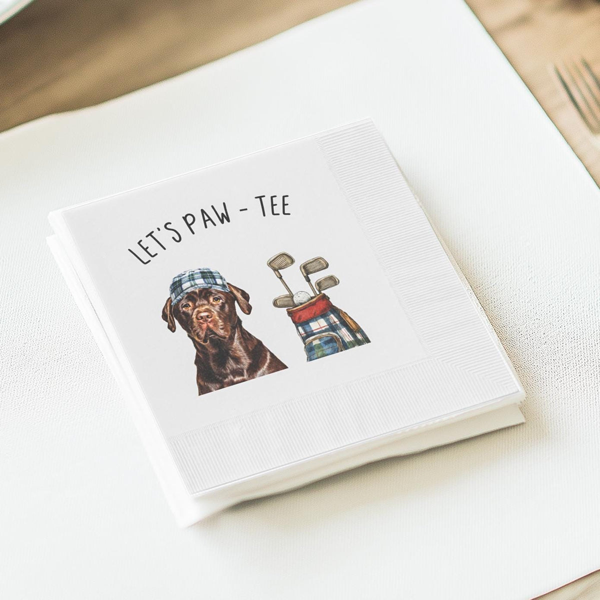 Custom cocktail napkin with a golf-themed dog design featuring a Labrador in a plaid cap, golf clubs, and the phrase 'Let’s Paw-Tee' — perfect for pet lovers’ golf parties, birthdays, and special events.