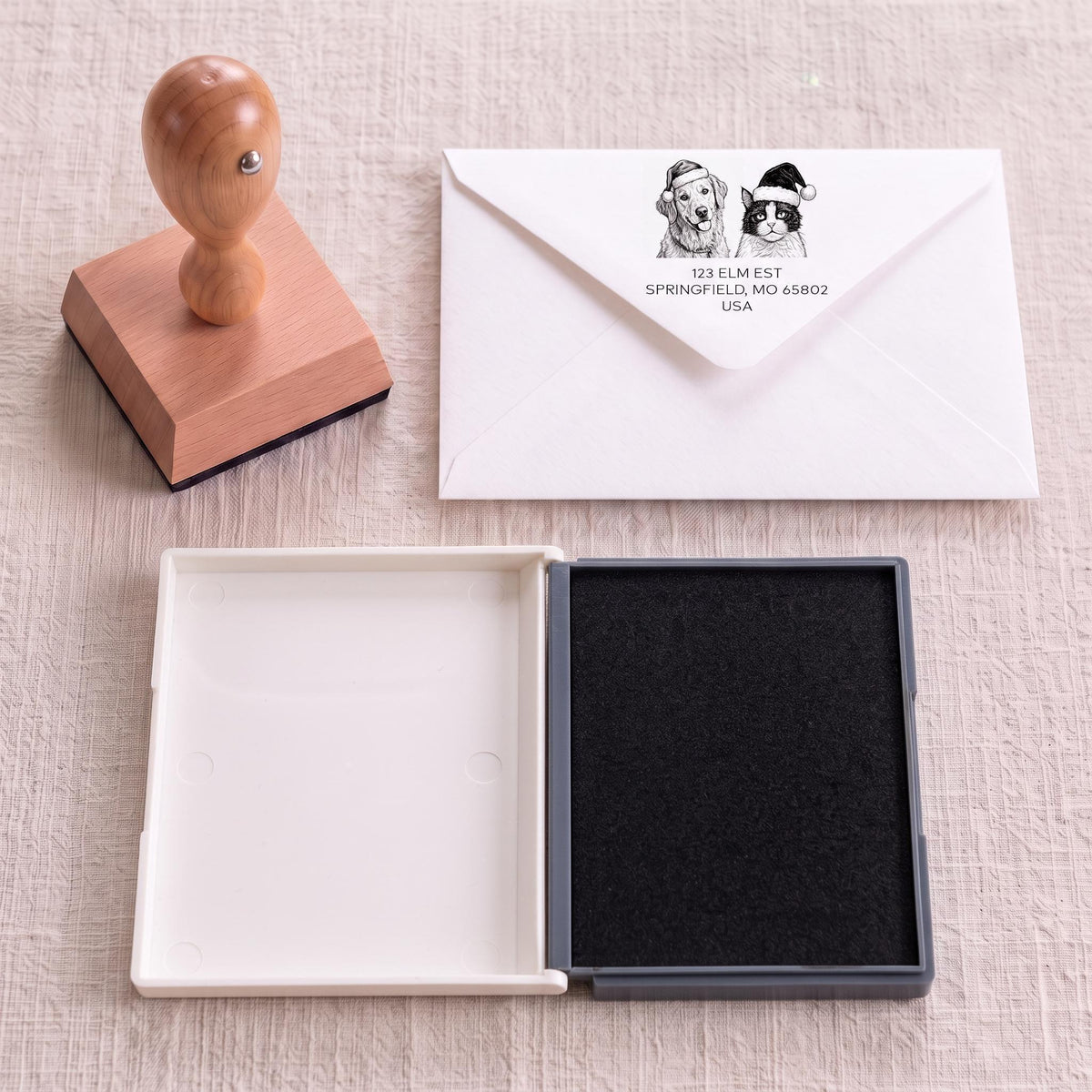 a wooden stamp, an envelope, and a white envelope with a black stamp on a table.