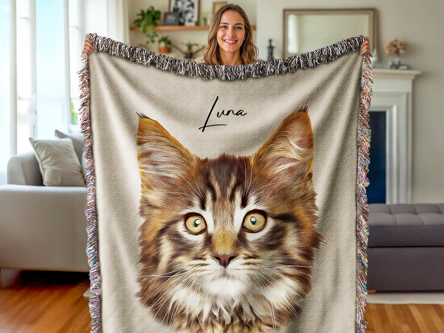 A woman holding a custom woven blanket featuring a detailed portrait of a fluffy tabby cat named Luna. The soft, fringed throw has a neutral background and a lifelike pet illustration, making it a cozy, personalized keepsake or memorial gift.