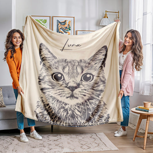 Two women proudly holding a beige blanket featuring a detailed black-and-white illustration of a cat with the name 'Luna' above it. The cozy personalized pet blanket adds a heartwarming touch to the stylish living room setting.