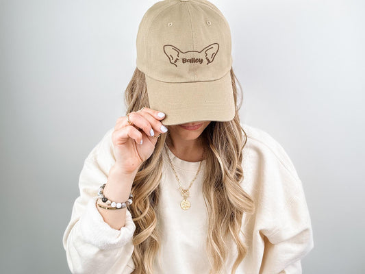 Beige custom embroidered cap featuring an outline of dog ears with the name 'Bailey' stitched in the center. A stylish and personalized gift for dog moms, dog dads, or pet lovers.