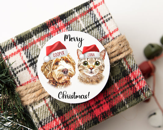 Festive sticker with a golden doodle, Cooper, and a tabby cat, Luna, both in Santa hats. 'Merry Christmas!' text on a wrapped plaid gift tied with rustic twine, perfect for holiday presents.